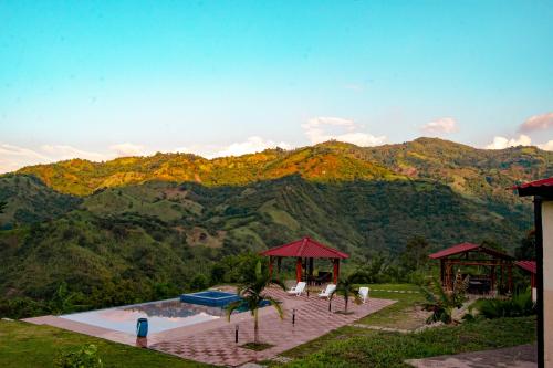 a pool with chairs and umbrellas in front of a mountain at Quinta Maka VistaHermosa in Villeta