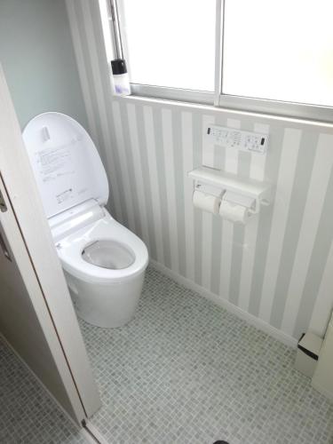 a bathroom with a white toilet with a window at Guest House OHANA in Kami-furano