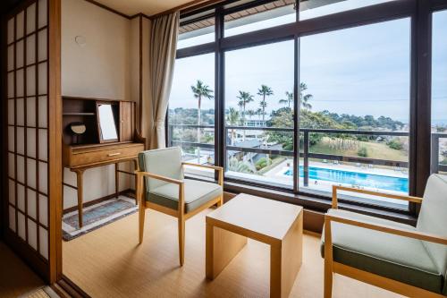 a living room with a desk and a large window at Infinito Hotel and Spa in Shirahama