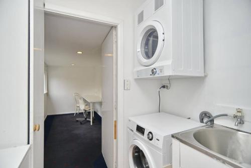 a kitchen with a washing machine and a sink at Hampstead Cottage in Christchurch