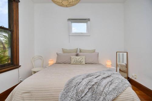 a white bedroom with a bed with a pillow on it at Hampstead Cottage in Christchurch