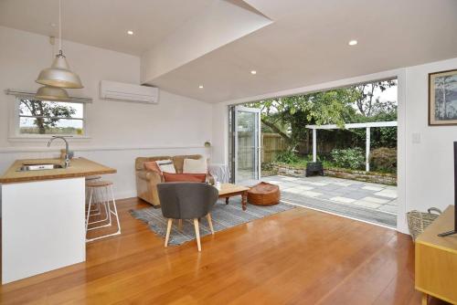 an open kitchen and living room with a view of a patio at Hampstead Cottage in Christchurch