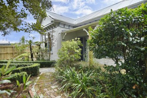 a white house with a garden in front of it at Hampstead Cottage in Christchurch
