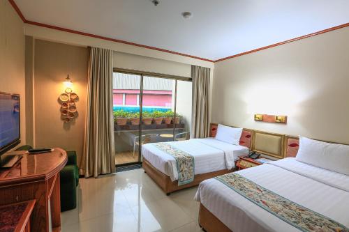 a hotel room with two beds and a television at Kosa Hotel & Wellness Center in Khon Kaen