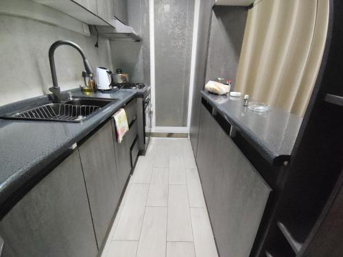 a small kitchen with black counters and a sink at DEPARTAMENTOS 3 DORMITORIOS, DESAYUNO, ESTACIONAMIENTo in Chillán