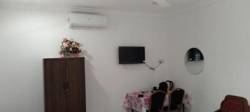 a room with a white wall with a cabinet and a tv at Noor Roomstay in Taiping