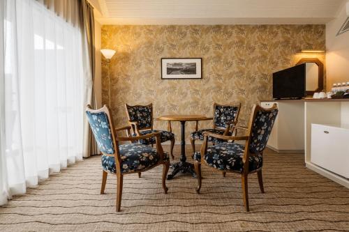 a room with a table and chairs and a television at Infinito Hotel and Spa in Shirahama