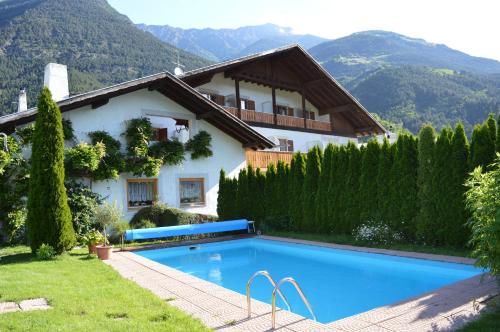 una villa con piscina di fronte a una casa di Pension Obergrundgut a Coldrano