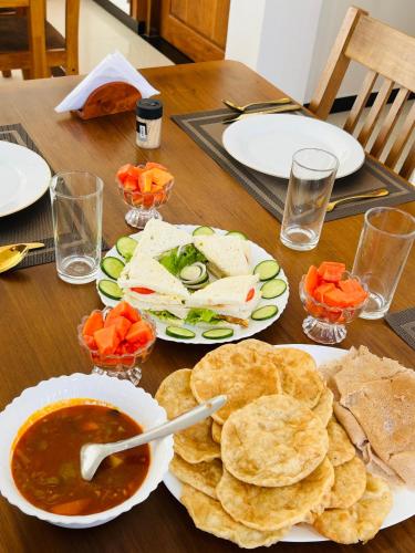 a wooden table topped with plates of food and dip at Jaffna City Palace Hotel in Jaffna