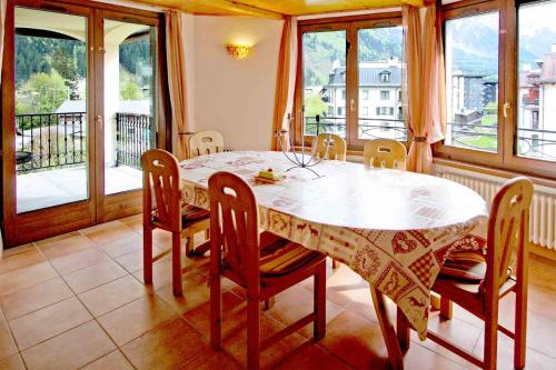 une salle à manger avec une table, des chaises et des fenêtres dans l'établissement Residence des Alpes 302 appt - Chamonix All Year, à Chamonix-Mont-Blanc
