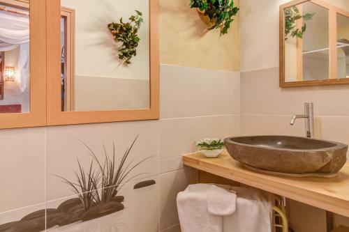 y baño con lavabo de piedra y espejos. en Hôtel des 4 continents - Le Mans, en Saint-Saturnin