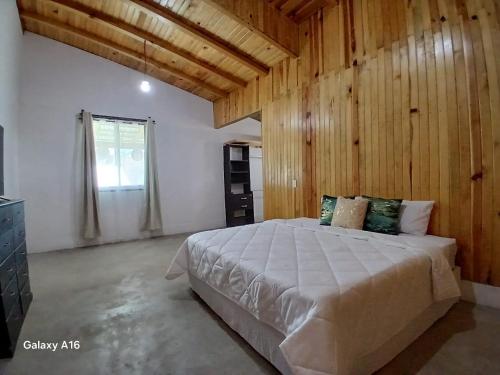 a bedroom with a large bed in a room with wooden walls at Hermosa Cabaña Familiar en Oaxaca in Oaxaca City