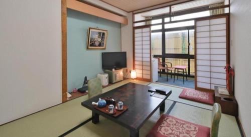 a living room with a table and a tv in it at Futami Onsen Hotel Seikai in Ise