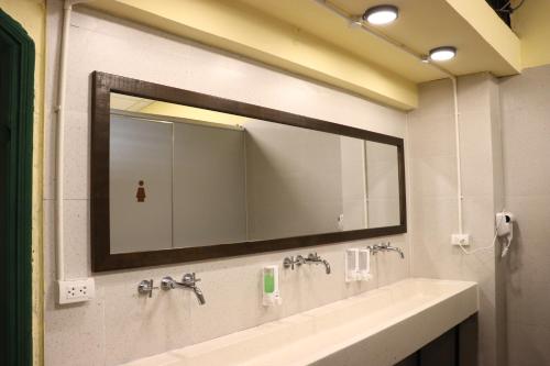 a bathroom with a large mirror and a sink at Rebel Rooster Hostel in Hanoi
