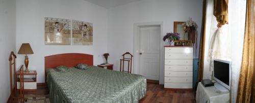 a bedroom with a bed and a dresser and a television at Sadiba Pri Dorogi in Kosiv