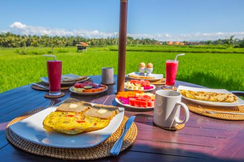 a table with plates of food and drinks on it at Uma Luwih Villa in Ubud