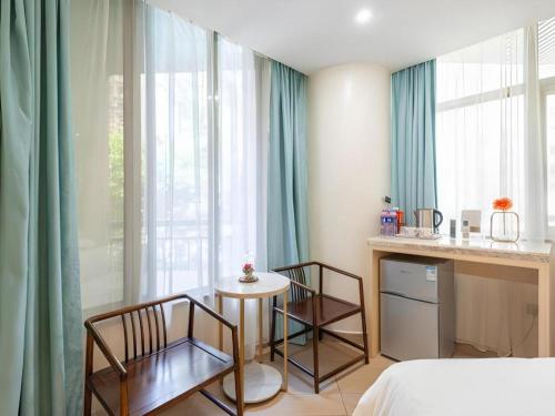 a bedroom with a bed and a table and chairs at Leisurely Hotel Shenzhen in Shenzhen