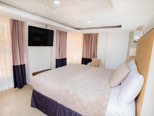 a hotel room with a bed and a flat screen tv at Muna Hotel in San Pedro Sula