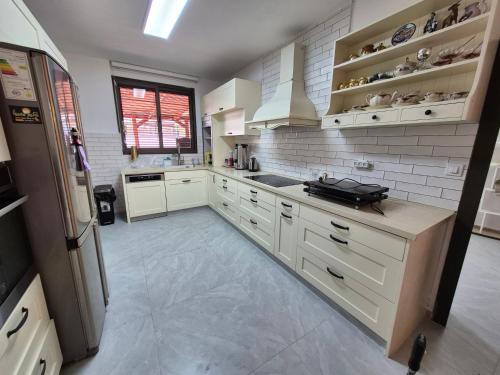 a large kitchen with white cabinets and a refrigerator at אירוח על הים in Ashqelon