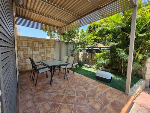 a patio with a table and chairs under a pergola at אירוח על הים in Ashqelon