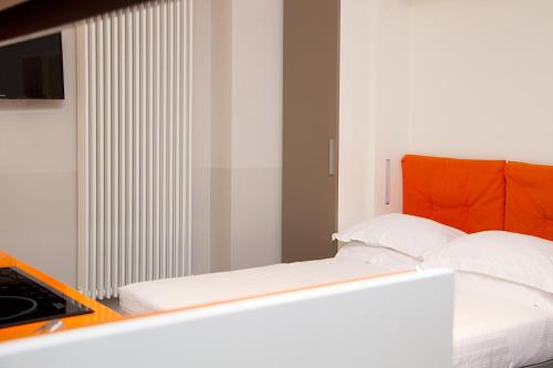 a white bed with an orange headboard in a room at Piazza Castello Suite in Turin