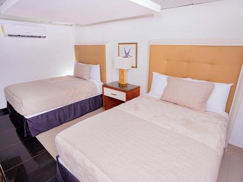 a hotel room with two beds and a lamp at Muna Hotel in San Pedro Sula