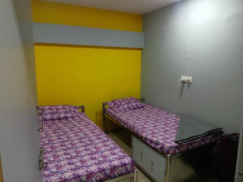 two beds in a room with yellow and purple at Shiv Sai Dormitory in Vadodara
