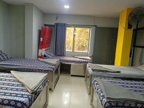 a group of beds in a room with a window at Shiv Sai Dormitory in Vadodara
