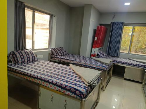 a room with three beds and a window at Shiv Sai Dormitory in Vadodara