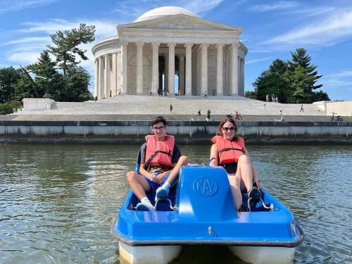 two people in a paddle boat in front of a building at River View Suite - The Wharf DC by Monthier in Washington