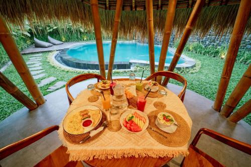Una mesa con un plato de comida y una piscina. en Balikayanas - Saputra House, en Selat