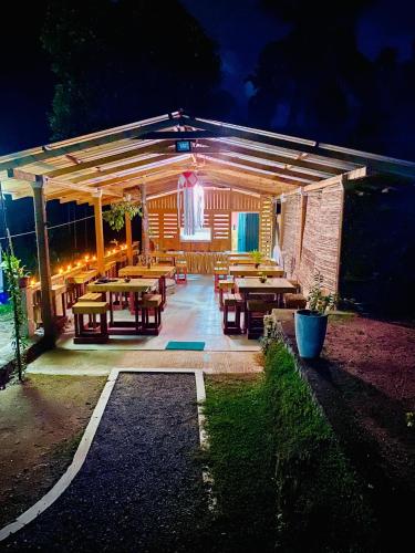 a patio with picnic tables and lights at night at komalie resort in Kitulgala