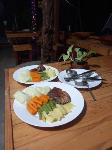 three plates of food on a wooden table at komalie resort in Kitulgala