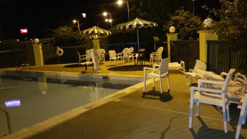 a group of white chairs sitting around a pool at night at Baymont by Wyndham Cave City in Cave City