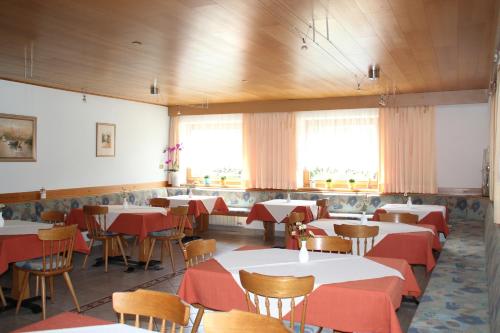 un comedor con mesas, sillas y ventanas en Pension Obergrundgut, en Coldrano