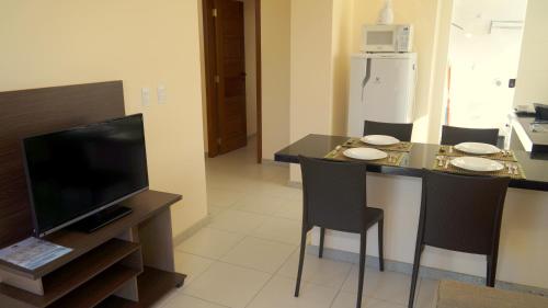 a kitchen with a table with chairs and a television at Residencial Portinari LTDA in Porto Seguro