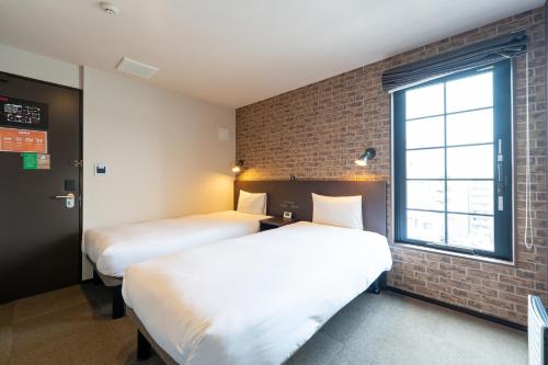 two beds in a room with a brick wall at HOTEL TABARD TOKYO - Vacation STAY 64570v in Tokyo