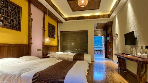 a hotel room with two beds and a television at Hongfu Villa - Zhangjiajie National Forest Park West Gate in Zhangjiajie