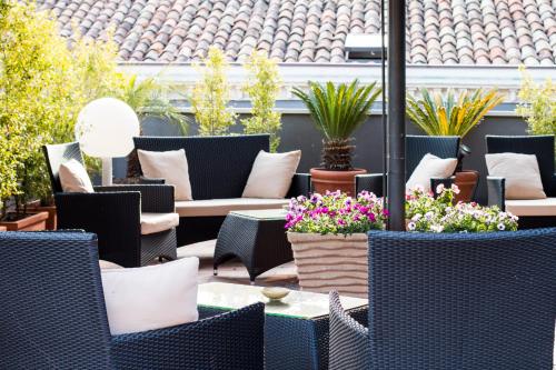 a patio with chairs and tables and potted plants at Dimora De Mauro in Catania