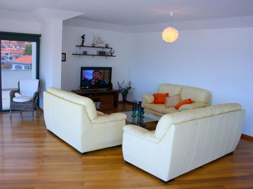 uma sala de estar com dois sofás brancos e uma televisão em V.I.P. Baia em Machico