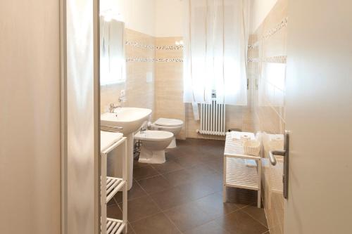 a white bathroom with a toilet and a sink at Gardenia Guest House in Forlì
