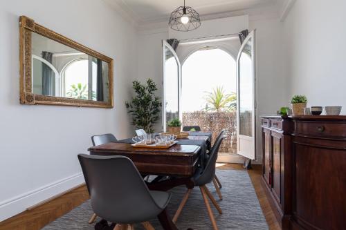 a dining room with a table and chairs and a mirror at Beautiful apartment by the sea front in Nice