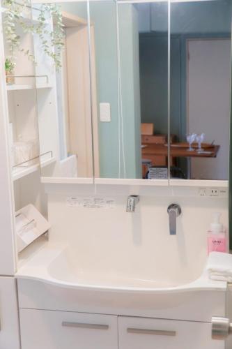 a white bathroom with a sink and a mirror at Dali's Nest Kamakura in Kamakura