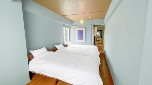 two beds in a blue room with white sheets at Dali's Nest Kamakura in Kamakura