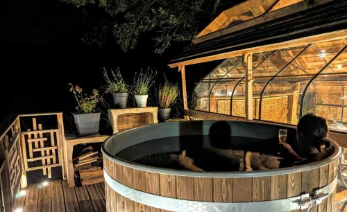 a person in a hot tub on a deck at night at La terre du milieu 87 in Saint-Sulpice-les-Feuilles