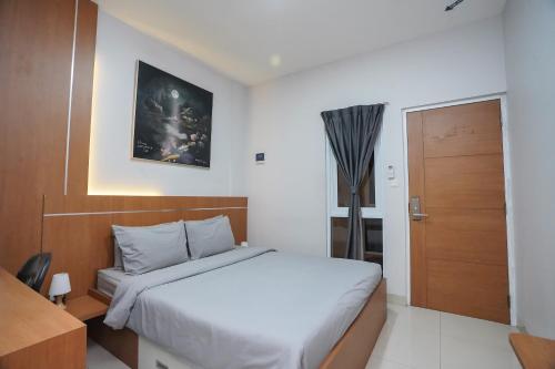 a bedroom with a white bed and a wooden door at DENZ Premiere Salemba in Jakarta