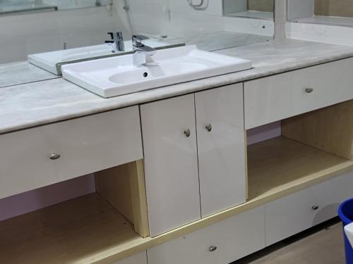 eine weiße Badezimmertheke mit einem Waschbecken und einem Spiegel in der Unterkunft Super Deluxe Room #1 in Ikeja