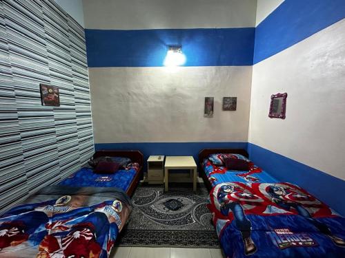 two beds in a room with blue and white walls at ziramike homestay in Kampong Baharu Sungai Udang