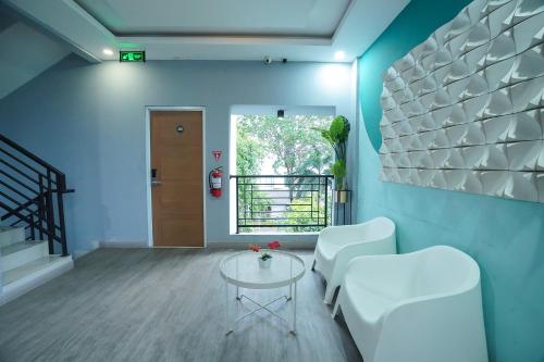 a living room with white chairs and a table at DENZ Premiere Salemba in Jakarta