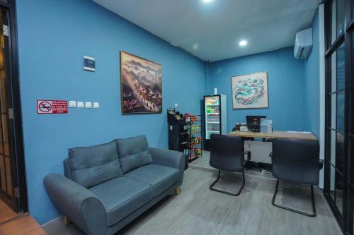 a blue room with a couch and a desk and a table at DENZ Premiere Salemba in Jakarta